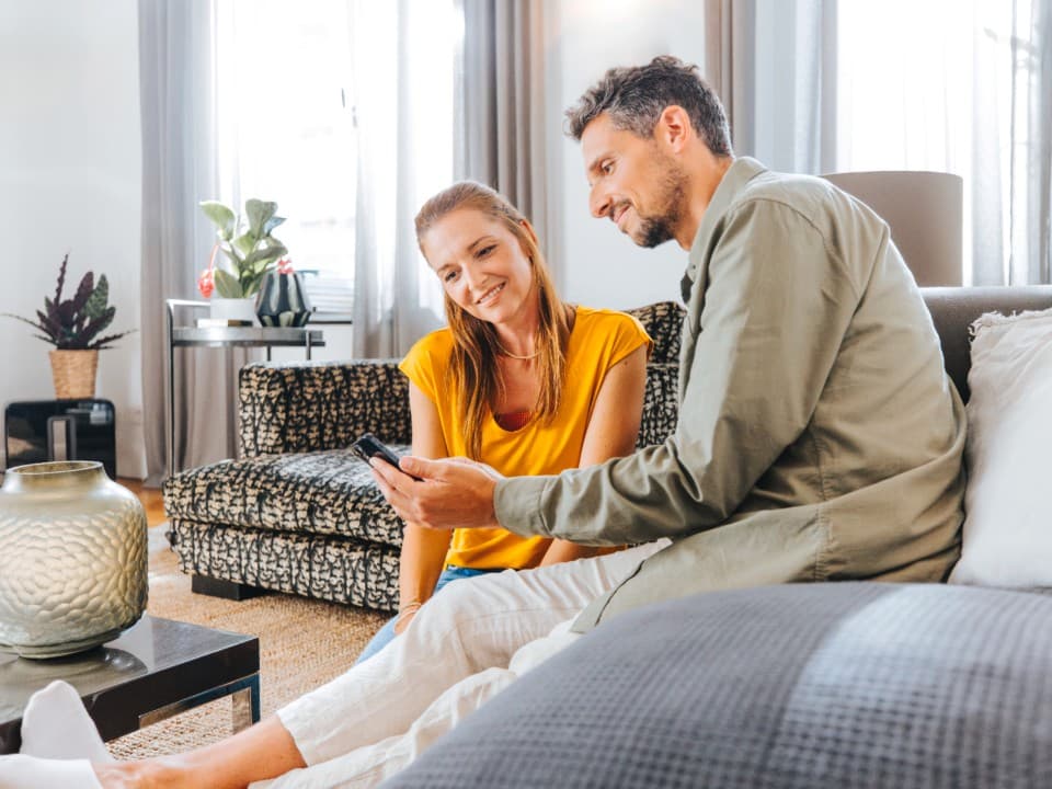 Un couple pilotant le chauffage à distance avec l'application myVAILLANT