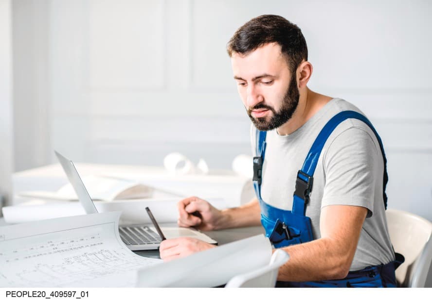 Un installateur travaillant sur des plans et son ordinateur portable